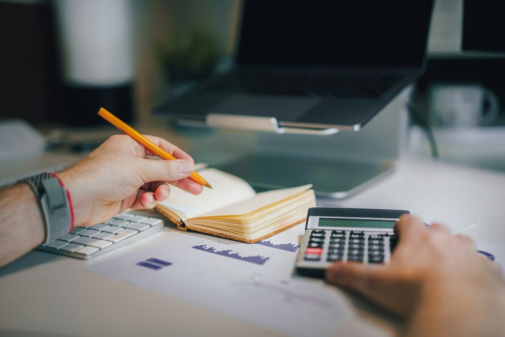 Una persona sentada en un escritorio con una calculadora y un cuaderno.